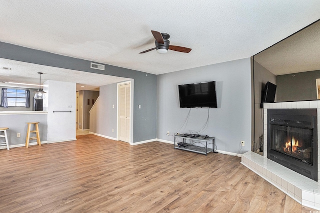 6703 Jefferson Pl Unit G5, Myrtle Beach, SC 29572 - unfurnished living room with a textured ceiling, a ceiling fan, wood finished floors, and a tile fireplace