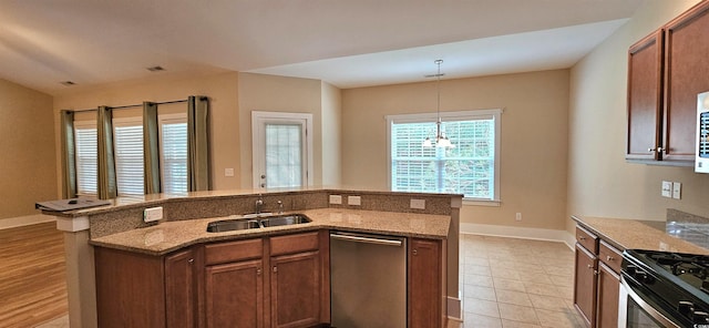 309 Outboard Dr, Murrells Inlet, SC 29576 - kitchen featuring appliances with stainless steel finishes, hanging light fixtures, light stone countertops, a center island with sink, and brown cabinets