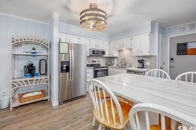 4201 N Ocean Blvd Unit 2M, North Myrtle Beach, SC 29582 - kitchen featuring appliances with stainless steel finishes, light countertops, white cabinets, backsplash, and light wood finished floors