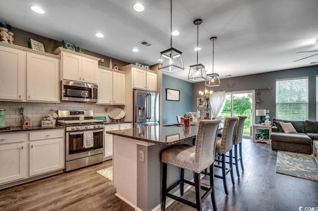 153 Goldenrod Cir Unit 7D, Little River, SC 29566 - kitchen featuring appliances with stainless steel finishes, decorative backsplash, wood finished floors, a breakfast bar, and a kitchen island