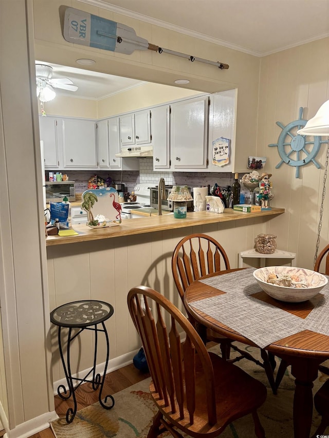 9501 Shore Dr Unit 323, Myrtle Beach, SC 29572 - kitchen featuring under cabinet range hood, ornamental molding, a peninsula, wood finished floors, and white stove