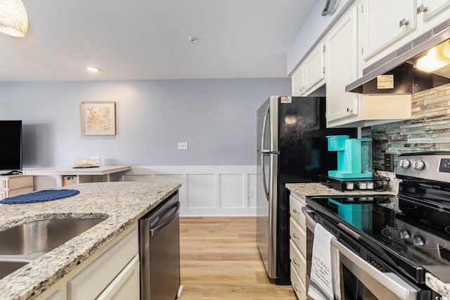 1210 N Ocean Blvd Unit 104, Surfside Beach, SC 29575 - kitchen featuring appliances with stainless steel finishes, under cabinet range hood, a wainscoted wall, light wood-style floors, and white cabinetry