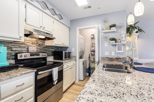 1210 N Ocean Blvd Unit 104, Surfside Beach, SC 29575 - kitchen featuring stainless steel appliances, stacked washer / dryer, under cabinet range hood, open shelves, and light stone countertops