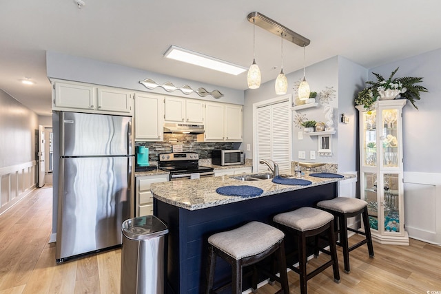 1210 N Ocean Blvd Unit 104, Surfside Beach, SC 29575 - kitchen featuring freestanding refrigerator, range with electric stovetop, under cabinet range hood, wainscoting, and light wood-style flooring