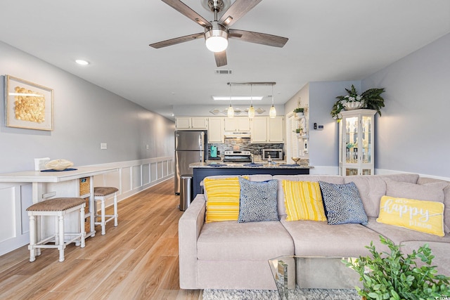 1210 N Ocean Blvd Unit 104, Surfside Beach, SC 29575 - living room with ceiling fan, light wood-style flooring, and a wainscoted wall