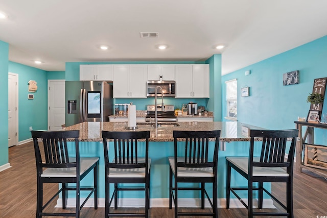 798 Woodland Farms Cir, Aynor, SC 29511 - kitchen with appliances with stainless steel finishes, white cabinetry, a kitchen island with sink, dark stone counters, and a kitchen bar