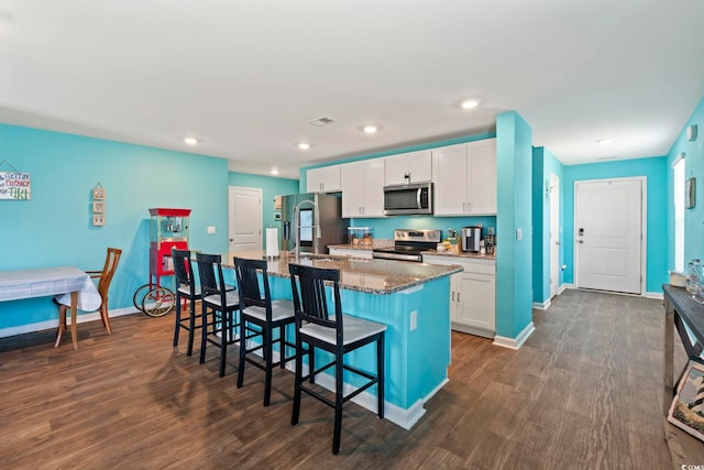 798 Woodland Farms Cir, Aynor, SC 29511 - kitchen featuring appliances with stainless steel finishes, an island with sink, a breakfast bar area, dark wood finished floors, and dark stone counters