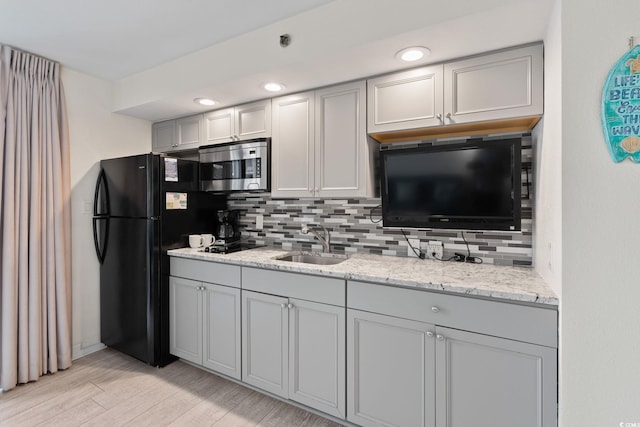 4800 S Ocean Blvd Unit 920, North Myrtle Beach, SC 29582 - kitchen with stainless steel microwave, backsplash, freestanding refrigerator, gray cabinets, and light stone counters