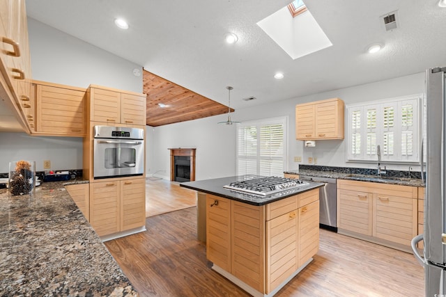149 Old Cedar Loop, Pawleys Island, SC 29585 - kitchen featuring appliances with stainless steel finishes, light brown cabinets, light wood-type flooring, a kitchen island, and a skylight