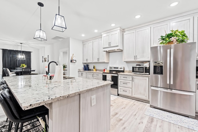 4486 Bethel Rd, Aynor, SC 29511 - kitchen with appliances with stainless steel finishes, light wood-type flooring, a kitchen island with sink, recessed lighting, and light stone countertops