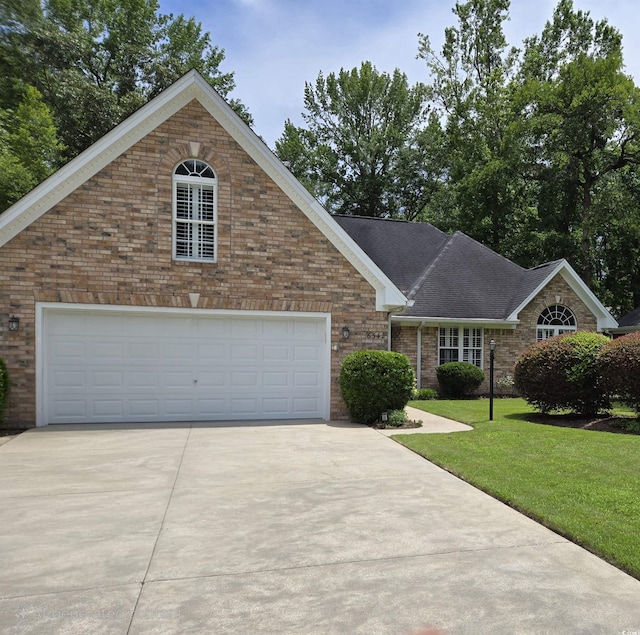 6542 Wellington Dr, Murrells Inlet, SC 29576 - view of front of house with concrete driveway, brick siding, a front lawn, and roof with shingles