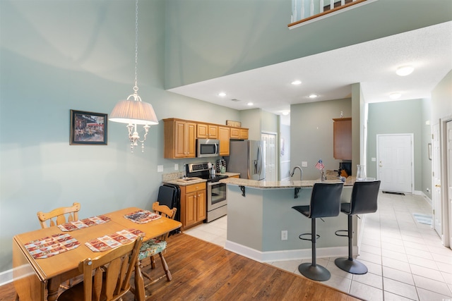 100 Culpepper Way Unit 1003, Myrtle Beach, SC 29579 - kitchen with stainless steel appliances, a peninsula, a kitchen bar, light stone counters, and light tile patterned floors