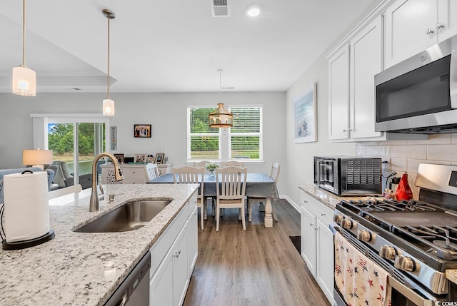 1898 Moonseed Dr, Longs, SC 29568 - kitchen featuring stainless steel appliances, light wood-type flooring, white cabinetry, decorative backsplash, and light stone countertops