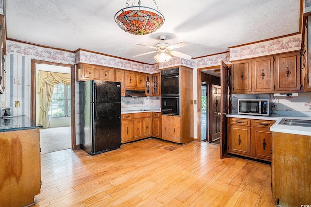 4920 Meadow St, Loris, SC 29569 - kitchen with black appliances, wallpapered walls, brown cabinetry, a ceiling fan, and light wood finished floors