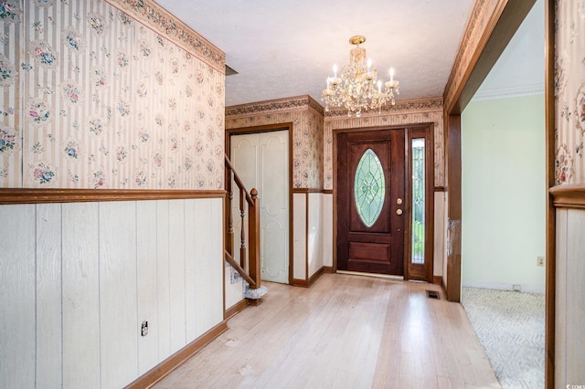 4920 Meadow St, Loris, SC 29569 - foyer entrance featuring a chandelier, light wood-style floors, wallpapered walls, crown molding, and stairs