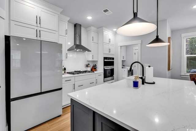 1216 Newell Dr, Myrtle Beach, SC 29588 - kitchen featuring freestanding refrigerator, wall chimney exhaust hood, stainless steel gas stovetop, white cabinetry, and hanging light fixtures