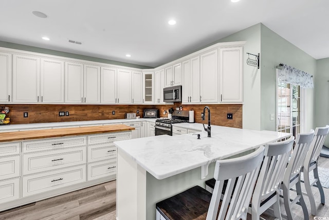 209 Haley Brooke Dr, Conway, SC 29526 - kitchen with stainless steel appliances, light wood-type flooring, a breakfast bar area, white cabinetry, and glass insert cabinets