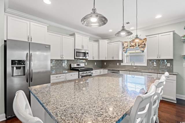 1715 Lake Egret Dr, North Myrtle Beach, SC 29582 - kitchen featuring stainless steel appliances, ornamental molding, white cabinets, light stone countertops, and a center island