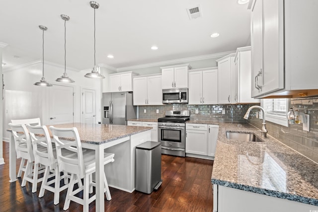 1715 Lake Egret Dr, North Myrtle Beach, SC 29582 - kitchen with appliances with stainless steel finishes, ornamental molding, white cabinetry, a center island, and tasteful backsplash