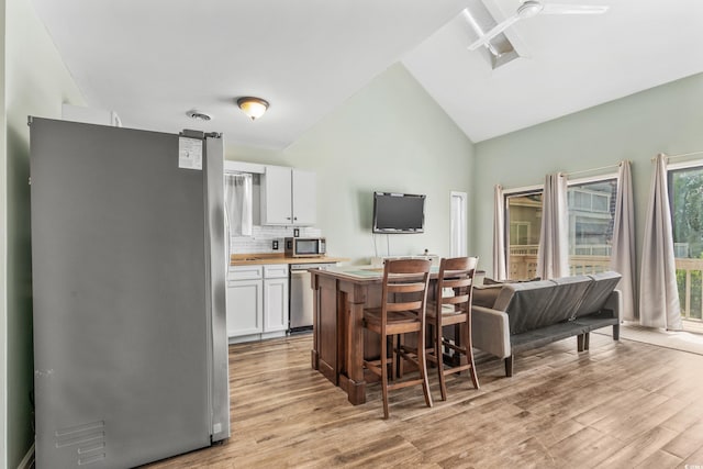 3700 Golf Colony Ln Unit 2-J, Little River, SC 29566 - kitchen with stainless steel appliances, white cabinets, light wood-type flooring, backsplash, and high vaulted ceiling