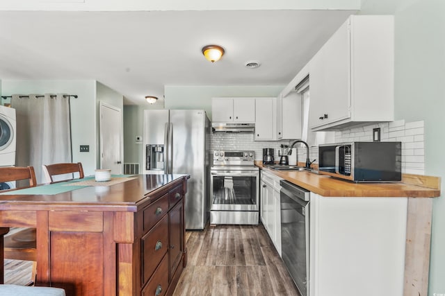 3700 Golf Colony Ln Unit 2-J, Little River, SC 29566 - kitchen featuring appliances with stainless steel finishes, under cabinet range hood, washer / dryer, butcher block counters, and dark wood-type flooring