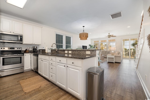 611 N Ocean Blvd, Surfside Beach, SC 29575 - kitchen featuring appliances with stainless steel finishes, a peninsula, wood finished floors, white cabinets, and recessed lighting