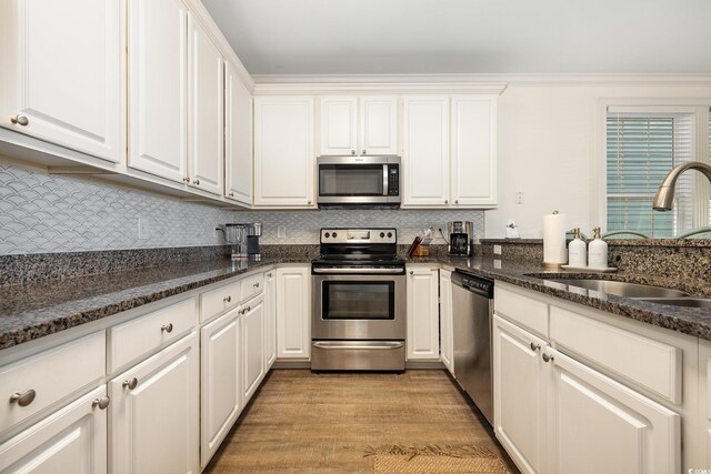 611 N Ocean Blvd, Surfside Beach, SC 29575 - kitchen with stainless steel appliances, light wood-type flooring, white cabinetry, decorative backsplash, and dark stone countertops