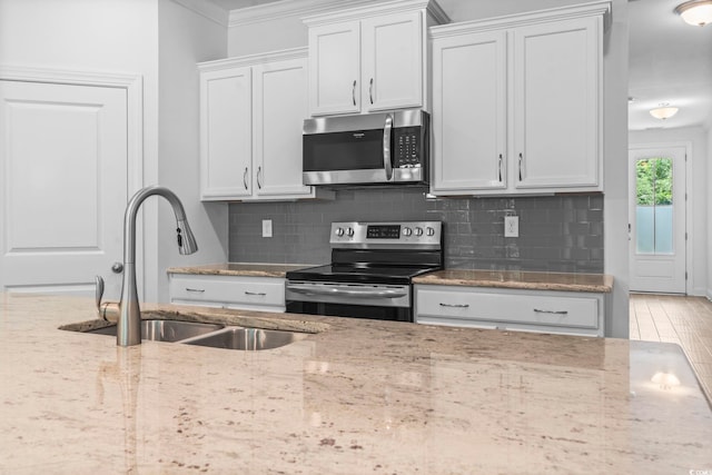 124 Castaway Key Dr, Pawleys Island, SC 29585 - kitchen featuring appliances with stainless steel finishes, tasteful backsplash, crown molding, light stone countertops, and white cabinets