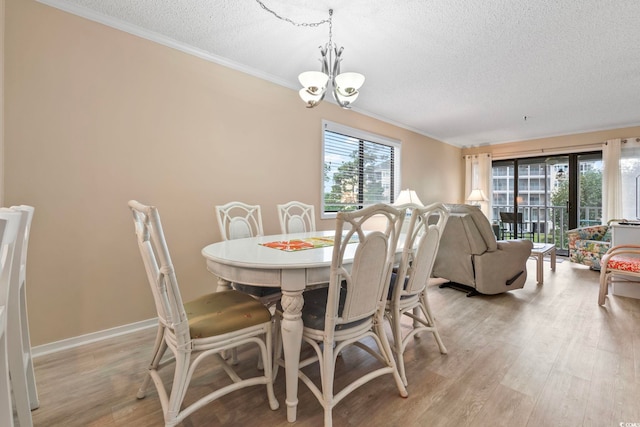305 Hillside Dr N Unit 205, North Myrtle Beach, SC 29582 - dining room featuring a textured ceiling, a chandelier, crown molding, healthy amount of natural light, and light wood-style floors