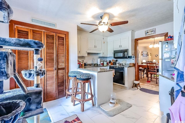 404 72nd Ave N Unit 301, Myrtle Beach, SC 29572 - kitchen with black microwave, stove, a peninsula, white cabinetry, and a ceiling fan