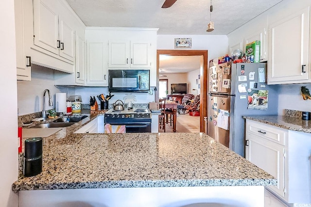 404 72nd Ave N Unit 301, Myrtle Beach, SC 29572 - kitchen with black appliances, white cabinets, a peninsula, light stone counters, and a ceiling fan