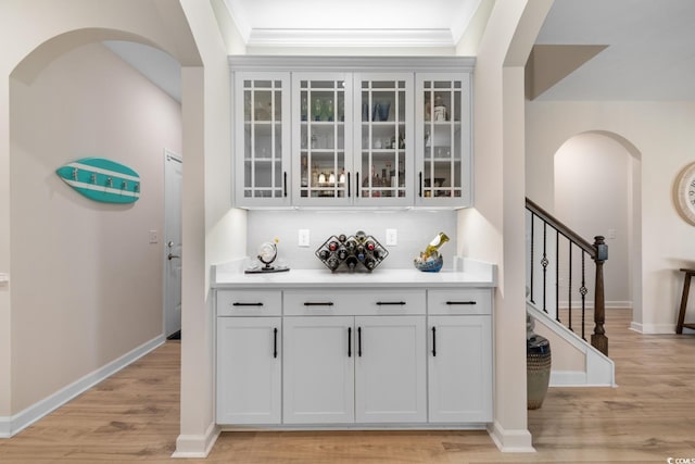 3185 Viceroy Loop, Little River, SC 29566 - bar area featuring light wood-style floors, arched walkways, decorative backsplash, stairway, and ornamental molding