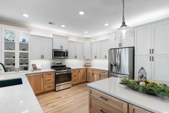 3185 Viceroy Loop, Little River, SC 29566 - kitchen with stainless steel appliances, light countertops, light wood-style floors, pendant lighting, and glass insert cabinets