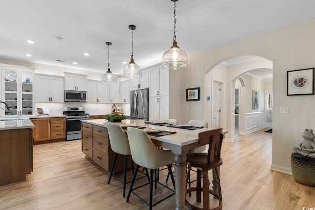 3185 Viceroy Loop, Little River, SC 29566 - kitchen featuring appliances with stainless steel finishes, a kitchen breakfast bar, arched walkways, light wood-style floors, and a center island