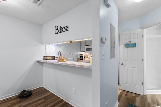 620 15th Ave S Unit 87, Surfside Beach, SC 29575 - kitchen featuring white microwave, a textured ceiling, dark wood finished floors, light countertops, and decorative backsplash