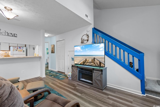 620 15th Ave S Unit 87, Surfside Beach, SC 29575 - living room featuring wood finished floors, stairway, a textured ceiling, and a glass covered fireplace