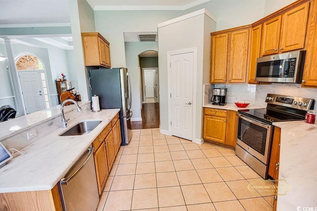 4499 Firethorne Dr, Murrells Inlet, SC 29576 - kitchen with appliances with stainless steel finishes, crown molding, light tile patterned floors, brown cabinets, and backsplash