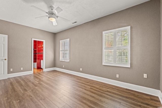3597 Sunfish St, Murrells Inlet, SC 29576 - unfurnished bedroom with multiple windows, wood finished floors, ensuite bath, a textured wall, and a ceiling fan