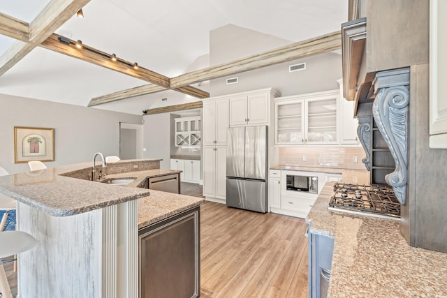 3597 Sunfish St, Murrells Inlet, SC 29576 - kitchen with stainless steel appliances, light wood-style floors, backsplash, white cabinetry, and a kitchen bar