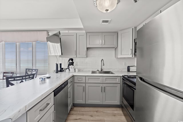 1605 S Ocean Blvd Unit 1403, Myrtle Beach, SC 29577 - kitchen featuring stainless steel appliances, gray cabinetry, decorative backsplash, light wood-style flooring, and light stone countertops