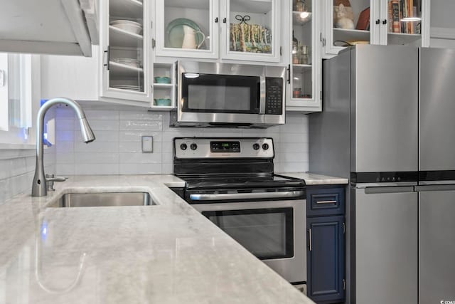 520 13th Ave N, Surfside Beach, SC 29575 - kitchen with appliances with stainless steel finishes, blue cabinetry, glass insert cabinets, and tasteful backsplash