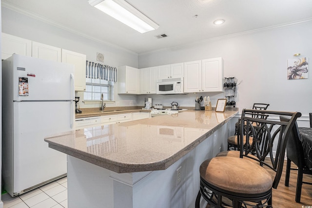 4868 Dahlia Ct Unit 202, Myrtle Beach, SC 29577 - kitchen featuring white appliances, a peninsula, white cabinets, crown molding, and a kitchen breakfast bar