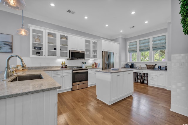 179 Cottage Ct, Pawleys Island, SC 29585 - kitchen with appliances with stainless steel finishes, ornamental molding, light stone counters, white cabinets, and recessed lighting