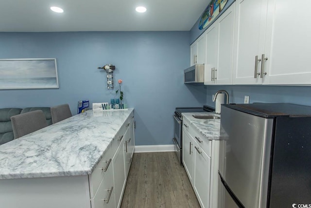 1207 S Ocean Blvd Unit 20403, Myrtle Beach, SC 29577 - kitchen featuring appliances with stainless steel finishes, a peninsula, dark wood-type flooring, white cabinetry, and recessed lighting