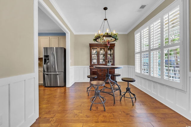 2199 Birchwood Cir, Myrtle Beach, SC 29577 - dining room with a chandelier, ornamental molding, a decorative wall, a wainscoted wall, and wood finished floors