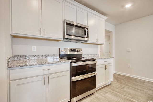 211 Seasons Trace Loop, Longs, SC 29568 - kitchen featuring appliances with stainless steel finishes, white cabinetry, light wood-type flooring, and light stone countertops