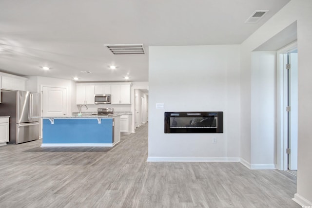 211 Seasons Trace Loop, Longs, SC 29568 - kitchen with appliances with stainless steel finishes, a breakfast bar area, light wood finished floors, white cabinetry, and recessed lighting