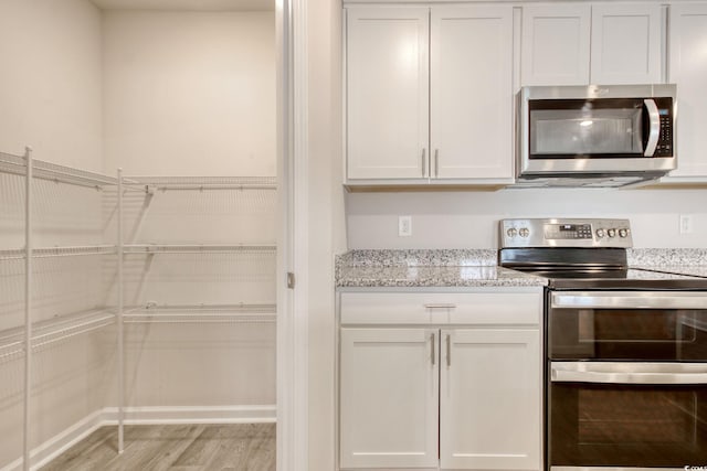 211 Seasons Trace Loop, Longs, SC 29568 - kitchen featuring appliances with stainless steel finishes, light wood-style floors, light stone countertops, and white cabinetry