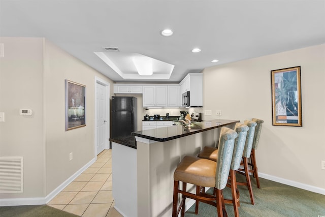 9994 Beach Club Dr Unit 1202, Myrtle Beach, SC 29572 - kitchen featuring freestanding refrigerator, a peninsula, a raised ceiling, white cabinets, and recessed lighting