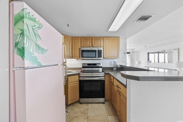 5511 N Ocean Blvd Unit 310, Myrtle Beach, SC 29577 - kitchen with appliances with stainless steel finishes, a peninsula, light tile patterned floors, and light brown cabinets